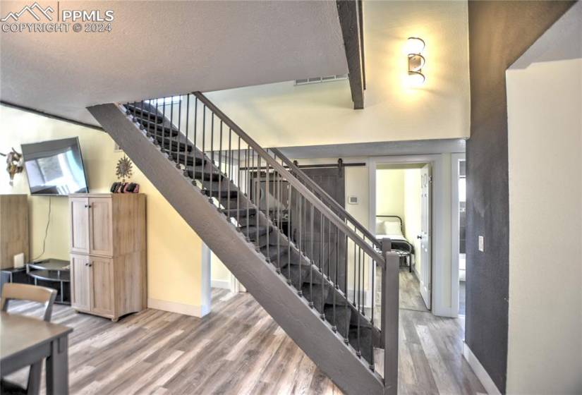 Stairway with a textured ceiling, a barn door, and light hardwood / wood-style floors