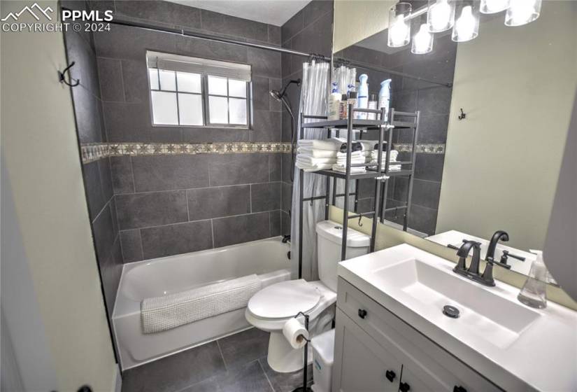 Full bathroom with vanity, toilet, shower / bath combination with curtain, and tile floors