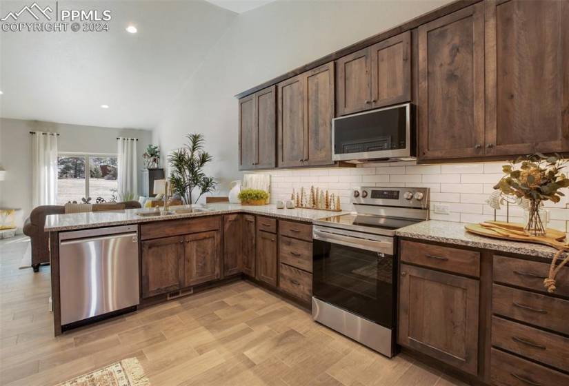 Kitchen featuring tasteful backsplash, dark brown cabinets, stainless steel appliances, and light stone counters