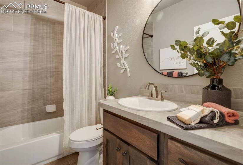 Full bathroom featuring large vanity, shower / bathtub combination with curtain, and toilet