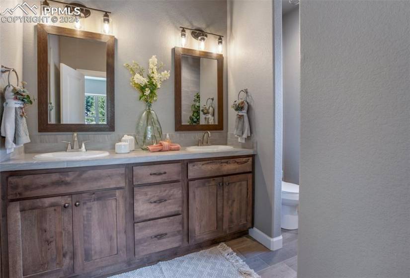 Bathroom featuring toilet, tile flooring, double sink, and vanity with extensive cabinet space