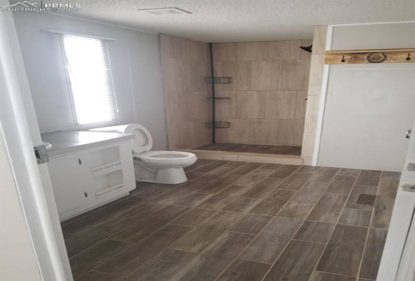 Bathroom featuring tiled shower, vanity, a textured ceiling, and toilet