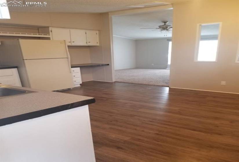 Kitchen with ceiling fan, white cabinetry, sink, white refrigerator, and dark colored carpet