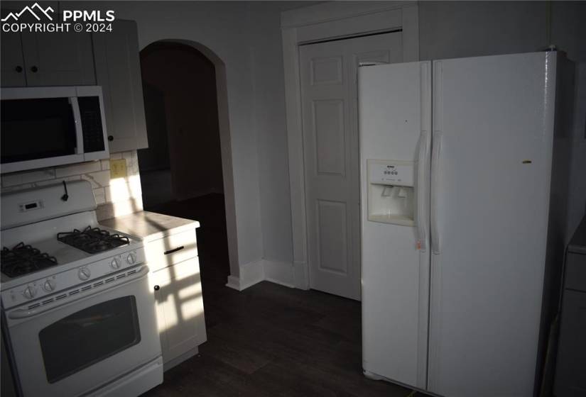 Kitchen featuring tasteful backsplash, white appliances, and dark hardwood / wood-style floors