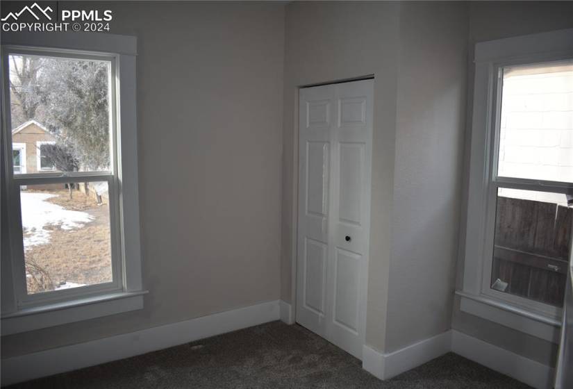 Unfurnished bedroom featuring dark colored carpet, multiple windows, and a closet