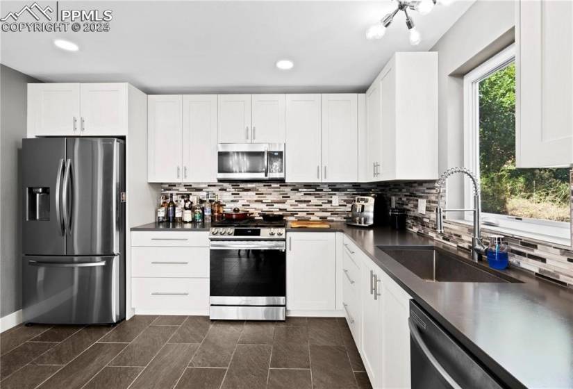 Kitchen featuring white cabinetry, stainless steel appliances, and tasteful backsplash