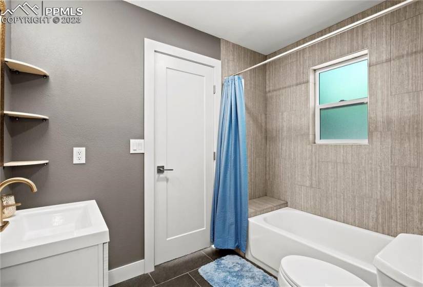 Full bathroom featuring shower / tub combo with curtain, vanity, tile flooring, and toilet
