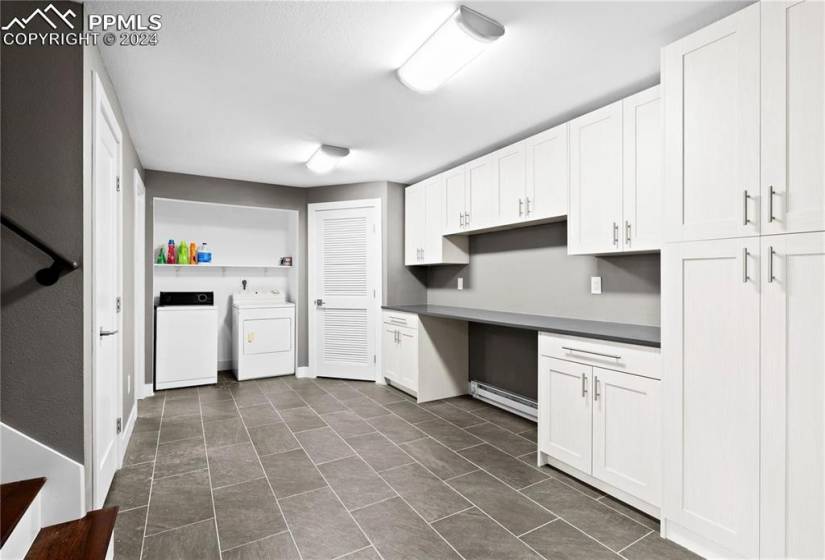 Kitchen featuring white cabinets, washer and clothes dryer, and dark tile floors