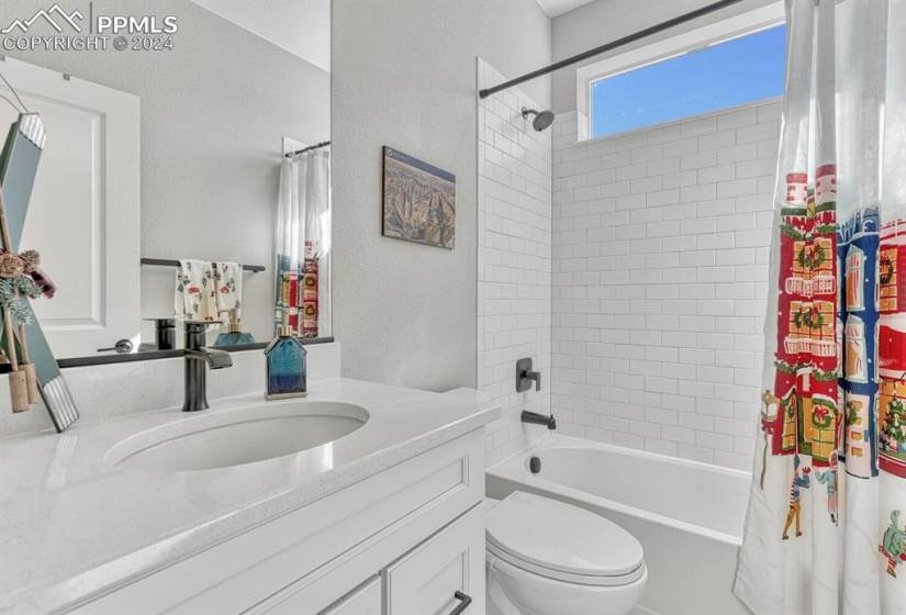 Full bathroom featuring shower / bath combo, vanity with extensive cabinet space, and toilet