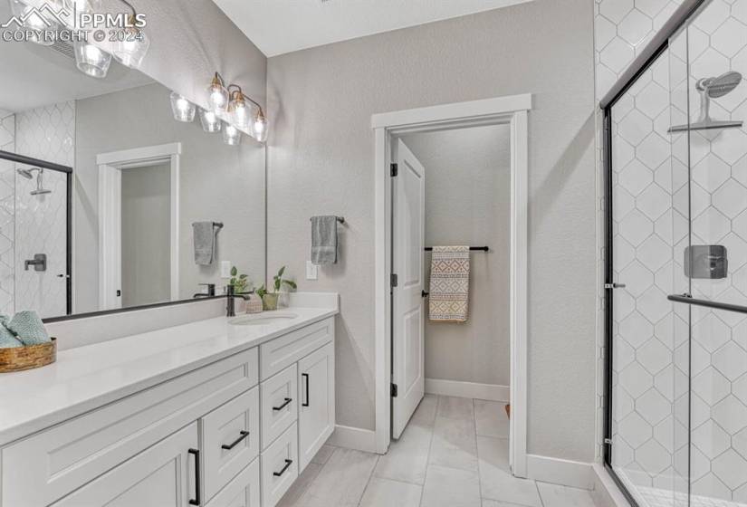 Bathroom featuring a shower with shower door, large vanity, and tile floors