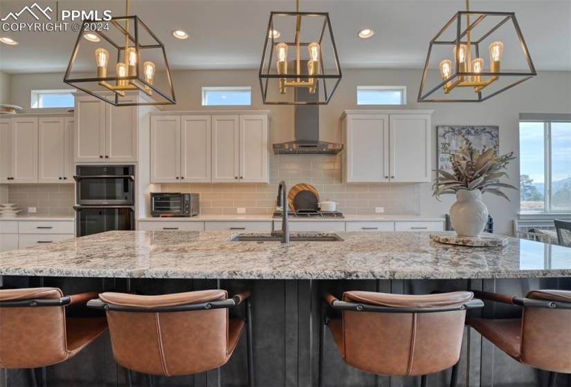 Kitchen with a wealth of natural light, backsplash, and wall chimney range hood