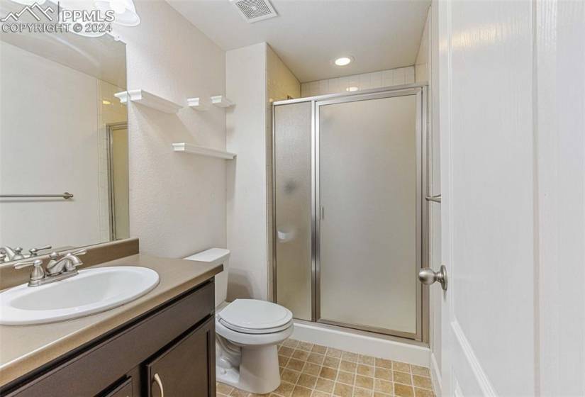 Bathroom with tile floors, vanity, toilet, and a shower with door