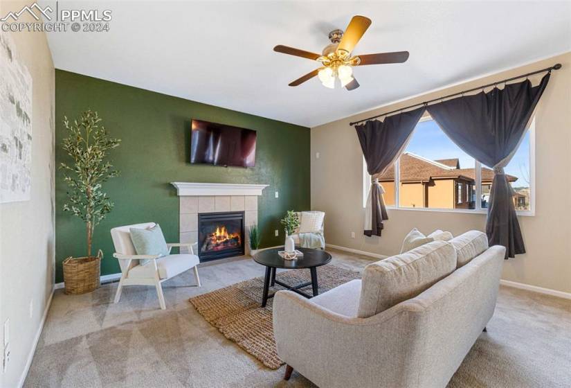 Carpeted living room with ceiling fan and a fireplace