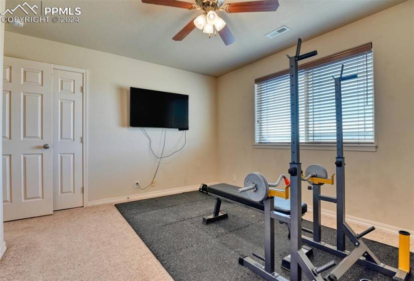 Workout room with light carpet and ceiling fan
