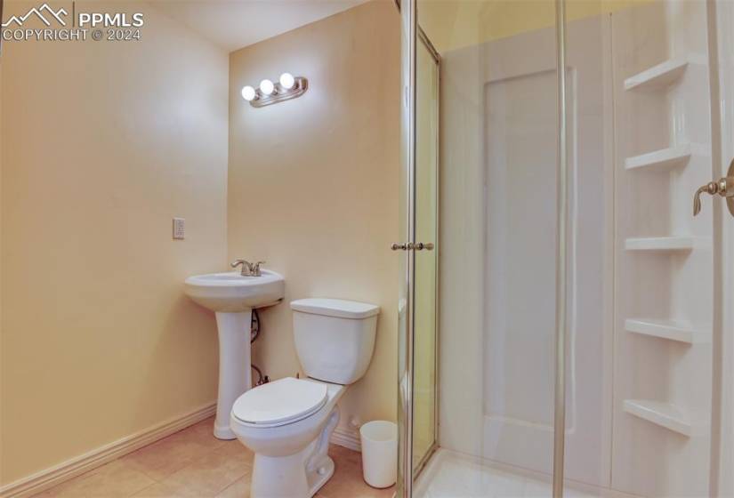 Bathroom with a shower with shower door, tile flooring, and toilet