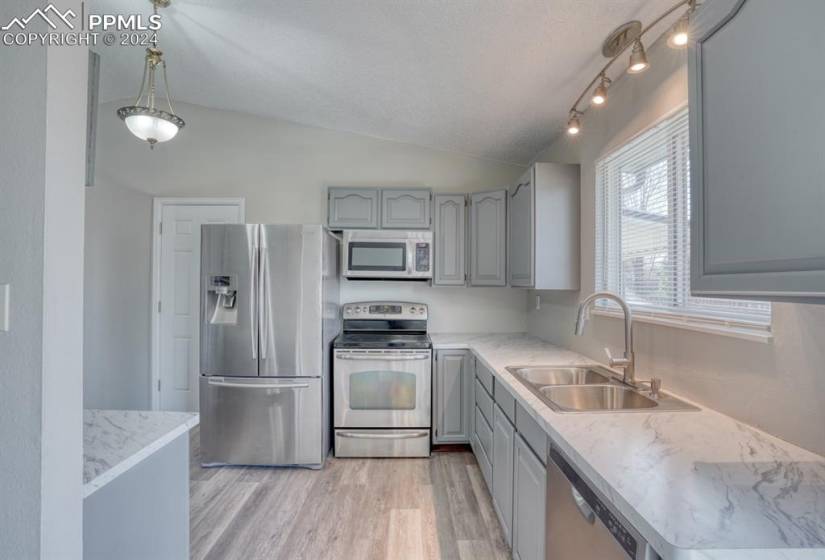 Kitchen featuring freshly painted cabinets, new countertops, stainless steel appliances, and garage access