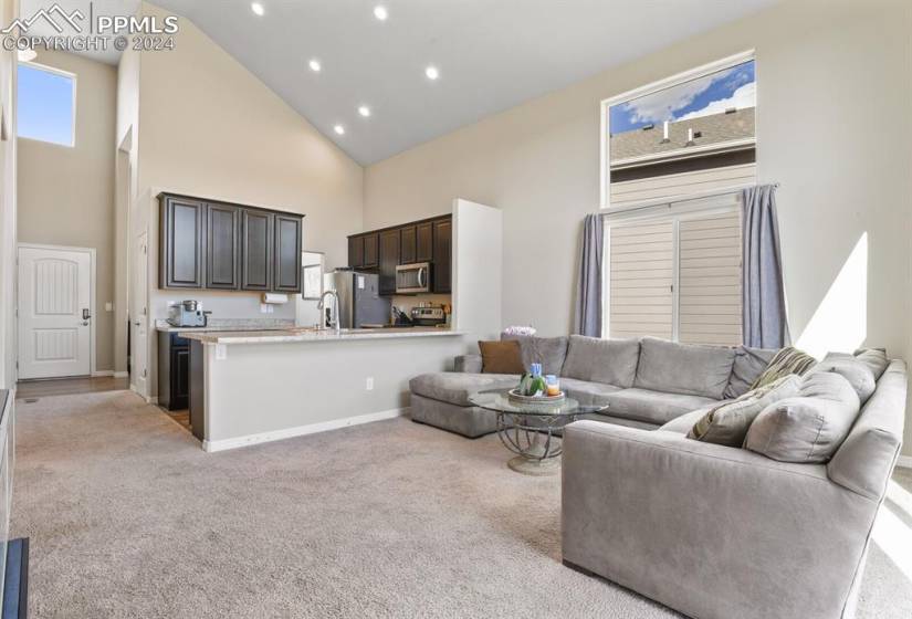 Carpeted living room featuring high vaulted ceiling.  Open to the kitchen.  Great floorplan for entertaining!