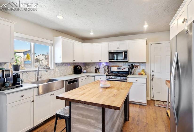 Kitchen with appliances with stainless steel finishes, white cabinets, a breakfast bar, and a kitchen island