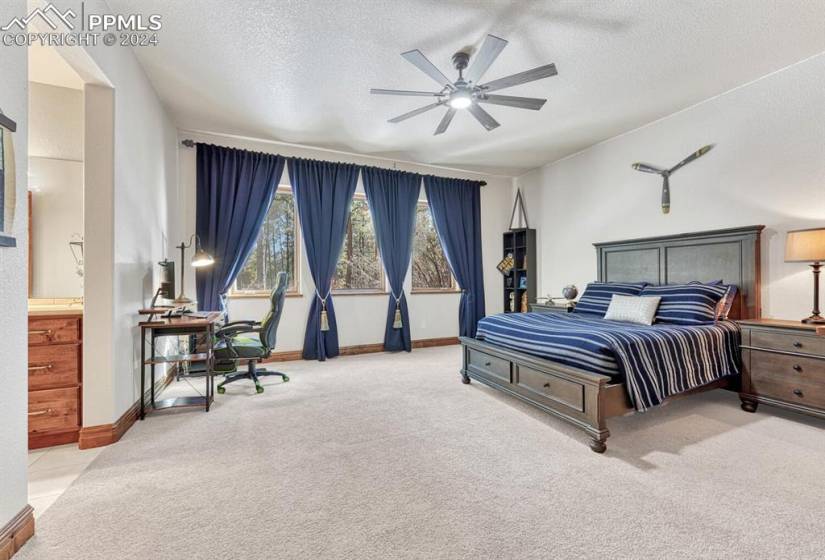 Basement Bedroom featuring light colored carpet, a textured ceiling, ensuite bath, and ceiling fan