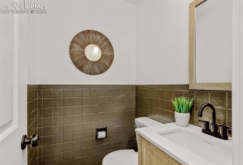 Bathroom with tasteful backsplash, tile walls, toilet, and vanity