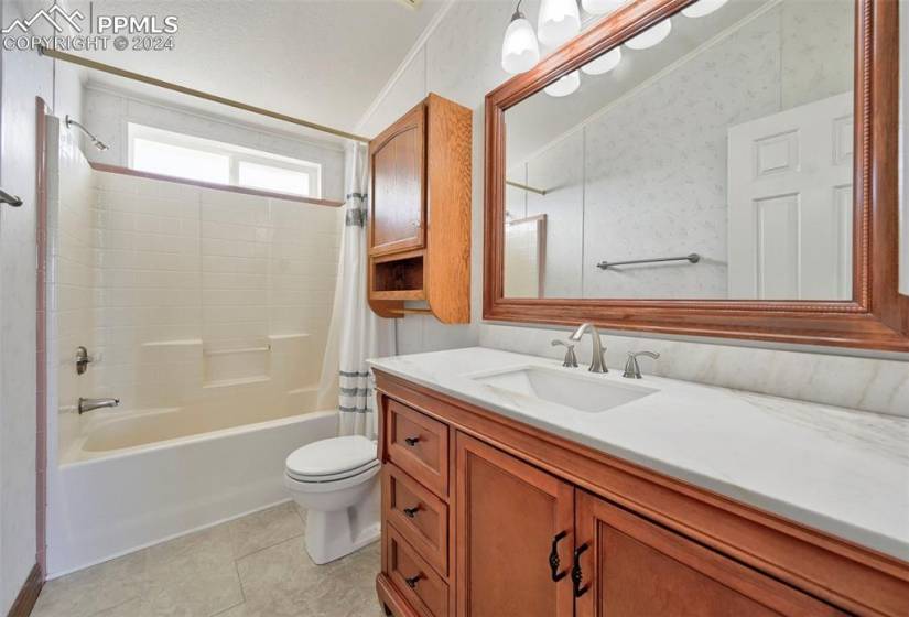 Full bathroom with shower / bathtub combination with curtain, ornamental molding, large vanity, and toilet