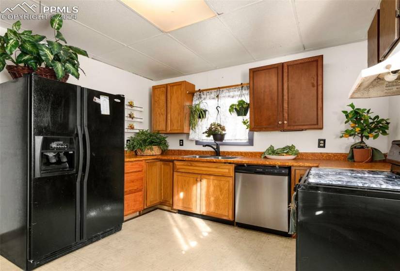 Kitchen featuring black appliances, sink, and light tile flooring
