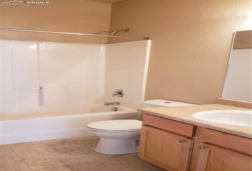 Full bathroom featuring vanity, toilet, tile flooring, and shower/tub combination