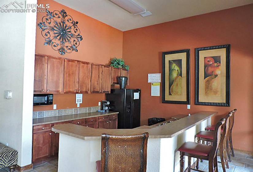 Clubhouse Kitchen with appliances, kitchen peninsula, a breakfast bar, and tile floors