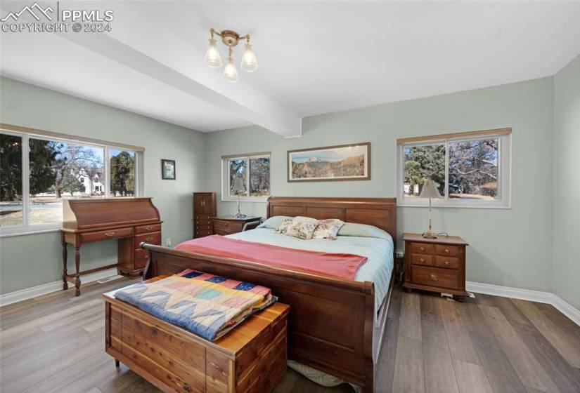 Bedroom with multiple windows, beamed ceiling, and hardwood / wood-style floors