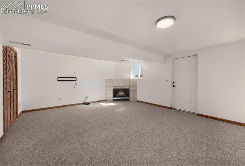 Unfurnished living room featuring light colored carpet and a tile fireplace