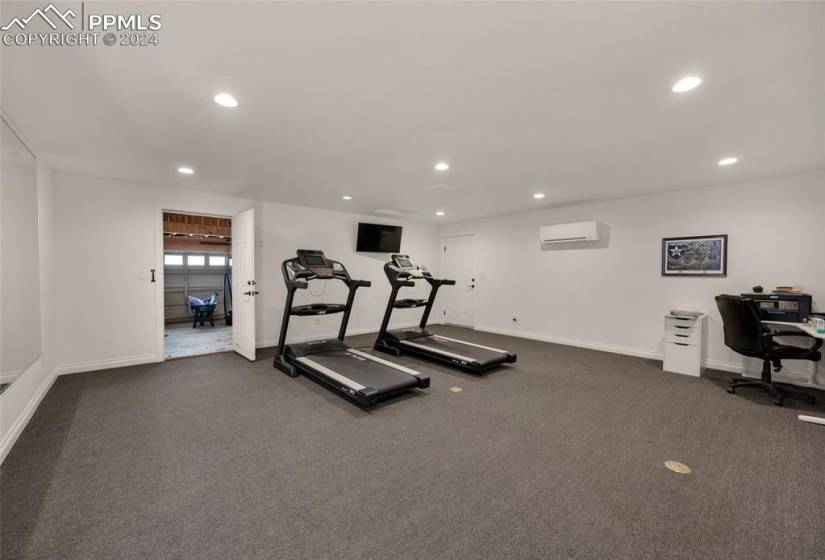 Workout room with dark colored carpet and a wall unit AC