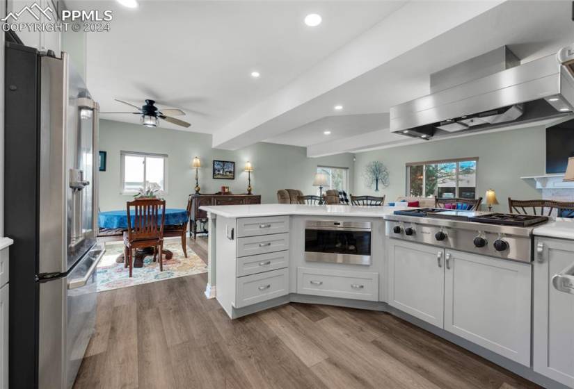 Kitchen with white cabinets, stainless steel appliances, ceiling fan, beam ceiling, and light wood-type flooring