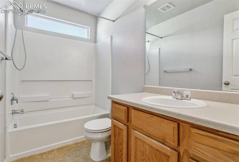 Full bathroom with toilet, bathing tub / shower combination, vanity with extensive cabinet space, and tile flooring