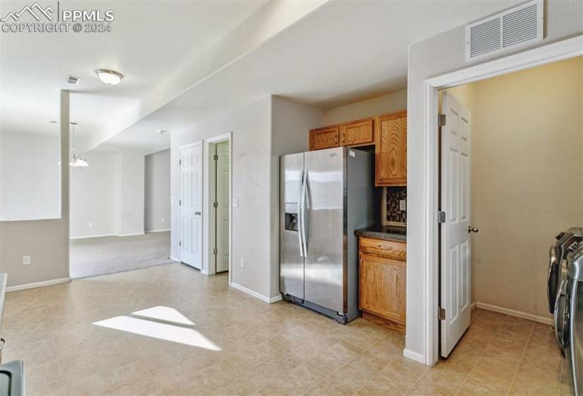 Kitchen with light tile flooring, tasteful backsplash, stainless steel fridge with ice dispenser, independent washer and dryer, and decorative light fixtures