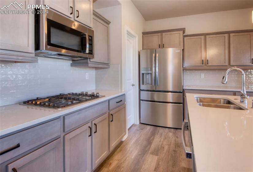 Kitchen featuring stainless steel appliances, tasteful backsplash, light hardwood / wood-style floors, and sink