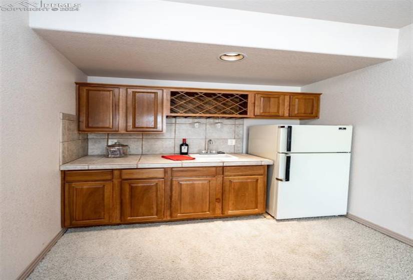 Wet bar with plenty of cabinets and refrigerator.