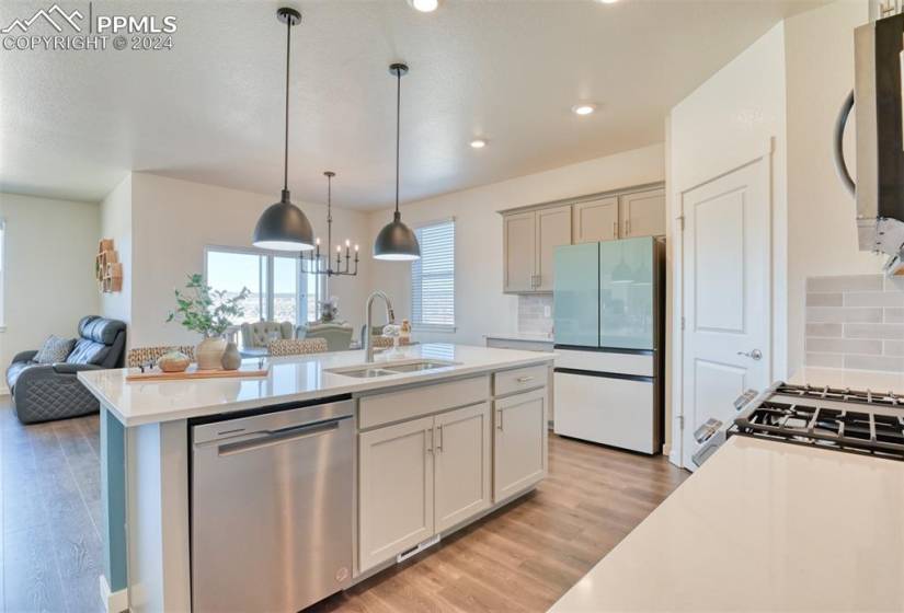 Kitchen featuring sink, decorative light fixtures, backsplash, light hardwood / wood-style flooring, and stainless steel appliances