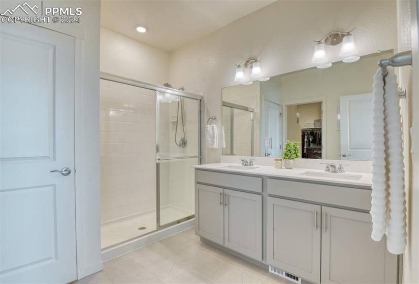 Bathroom featuring an enclosed shower, double sink, oversized vanity, and tile flooring