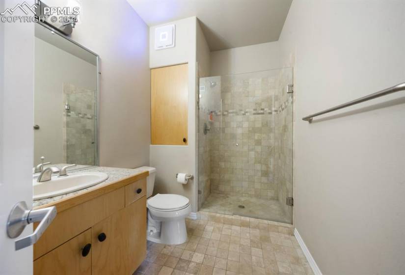 Bathroom with oversized vanity, tile floors, toilet, and walk in shower