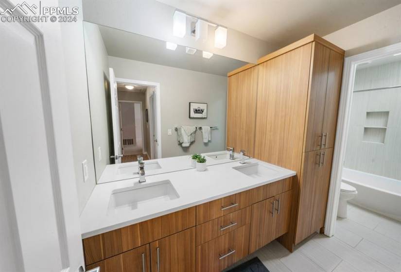 Full bathroom with dual bowl vanity, toilet,  shower combination, and tile floors