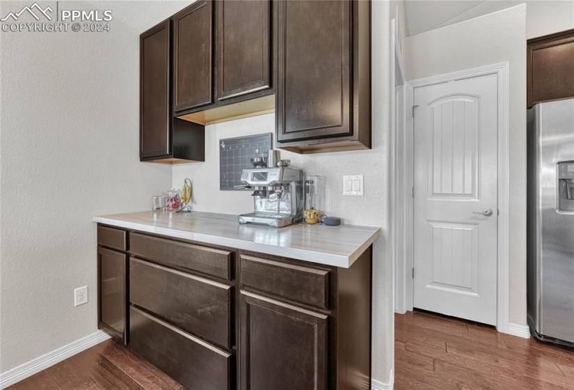 Kitchen with backsplash, stainless steel fridge, dark hardwood / wood-style flooring, and dark brown cabinets