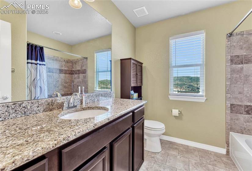 Full bathroom featuring vanity, shower / bath combo, a healthy amount of sunlight, and tile floors