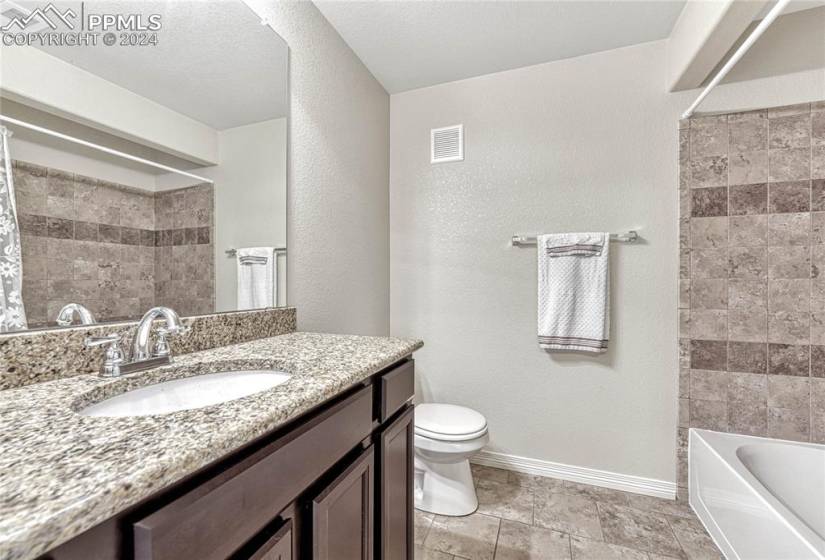 Full bathroom featuring shower / bathtub combination with curtain, tile walls, toilet, tile flooring, and oversized vanity