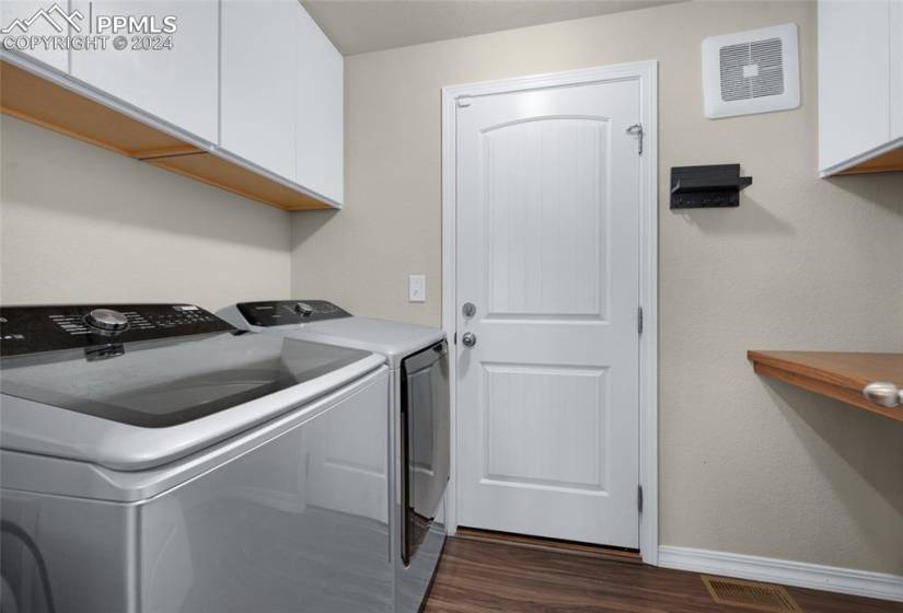 Laundry area featuring cabinets, washing machine and dryer, and dark wood-type flooring