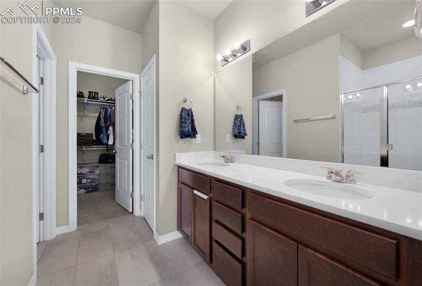 Bathroom with tile flooring, double sink vanity, and walk in shower