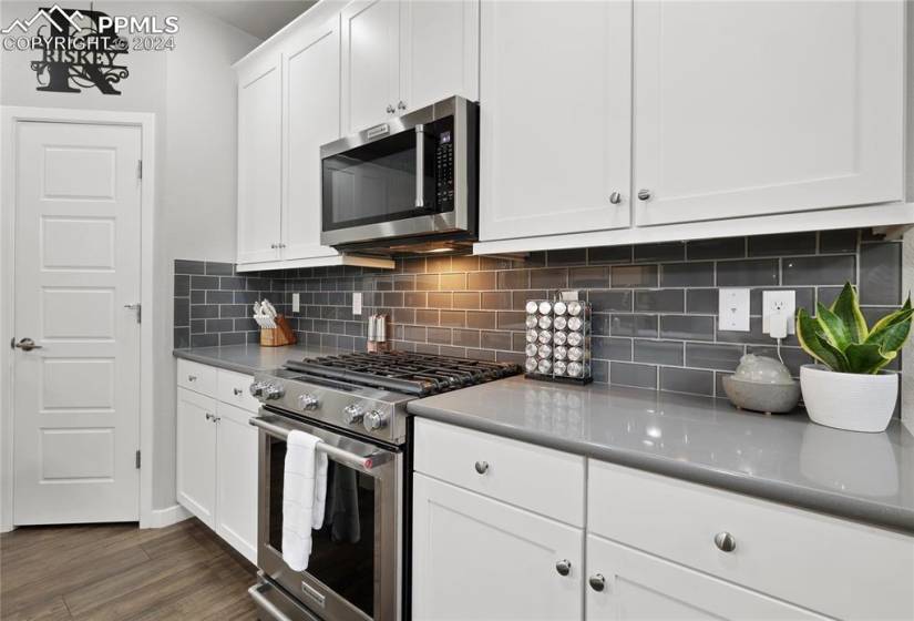 Kitchen featuring stainless steel appliances, white cabinetry, dark hardwood / wood-style flooring, and tasteful backsplash