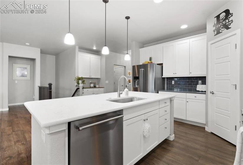 Kitchen featuring appliances with stainless steel finishes, white cabinets, a kitchen island with sink, and dark wood-type flooring
