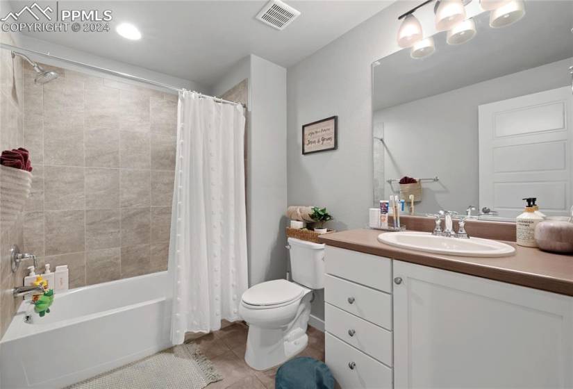 Full bathroom featuring oversized vanity, shower / bathtub combination with curtain, tile floors, and toilet