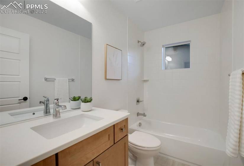 Full bathroom featuring vanity, toilet, tile flooring, and tiled shower / bath