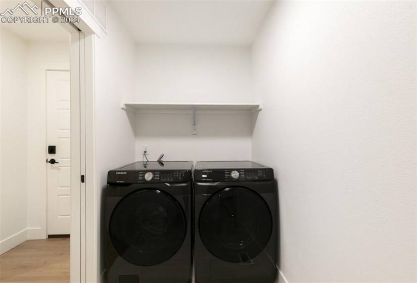Clothes washing area featuring light hardwood / wood-style floors and washing machine and clothes dryer